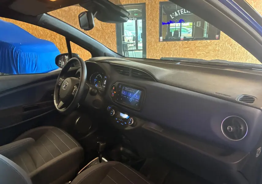 Vue intérieure côté conducteur de la Toyota Yaris 2020, tableau de bord noir avec écran tactile et volant multifonction.