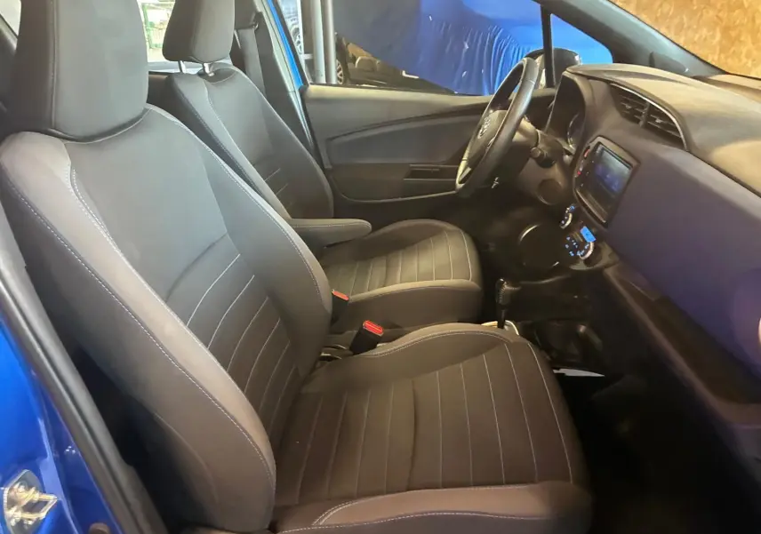 Intérieur de la Toyota Yaris 2020 bleu, vue côté gauche, sièges tissu noirs et tableau de bord avec écran tactile.