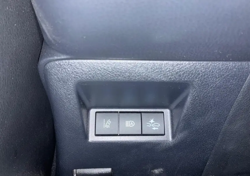 Gros plan sur les trois boutons de commande situés à gauche du tableau de bord dans une Toyota Yaris hybride bleue de 2020.