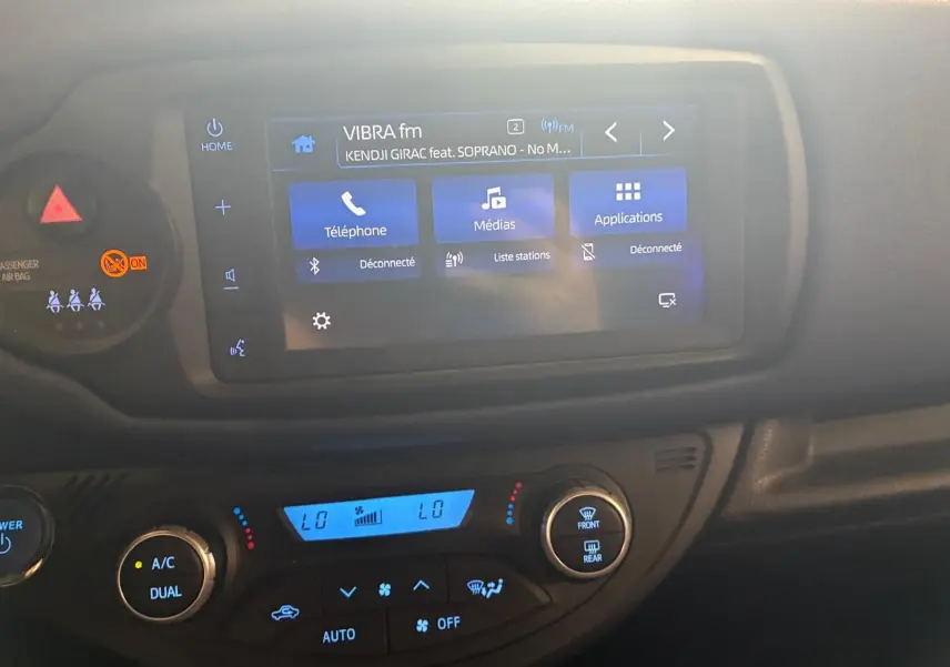 Vue rapprochée de l’écran tactile et de la console de climatisation d’une Toyota Yaris hybride 2020, intérieur noir.