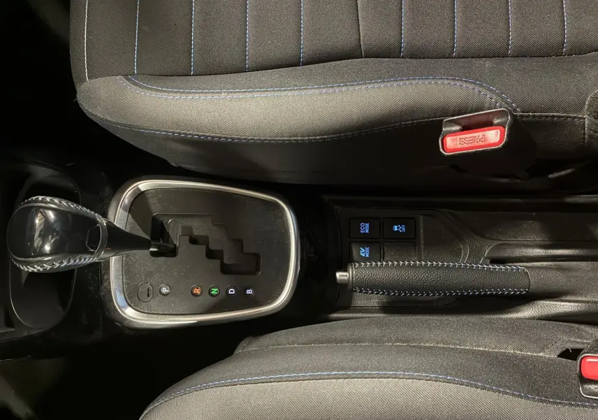 Vue plongeante sur la console centrale de la Toyota Yaris hybride bleue 2020, avec levier de vitesse automatique et frein à main.