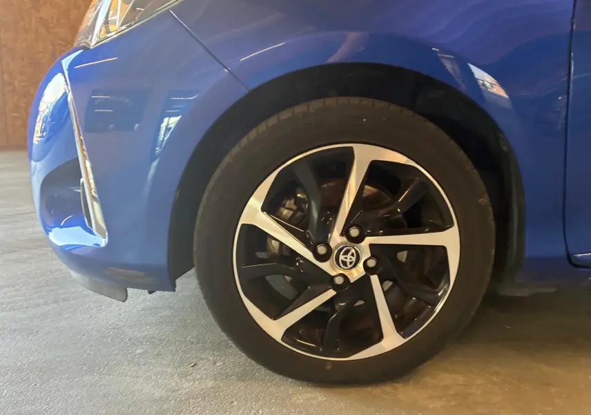 Gros plan sur la roue avant gauche d'une Toyota Yaris hybride bleue 2020, avec jante alliage bicolore et logo Toyota visible.