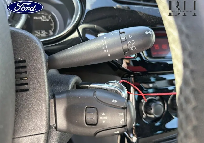 Gros plan sur la commande au volant et le commodo d’essuie-glace d’une Citroën DS3 rouge Rubi, intérieur noir.
