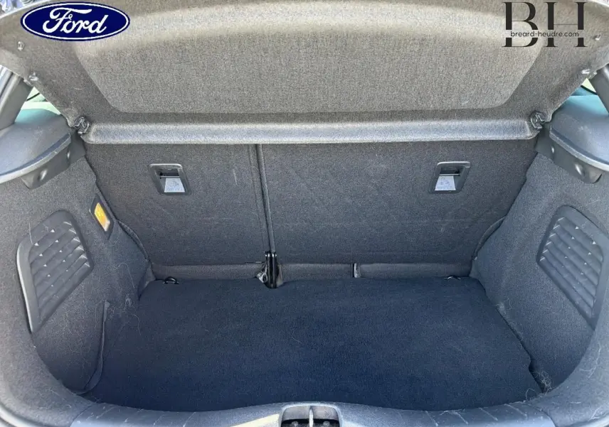 Coffre ouvert vu de face d'une Citroën DS3 rouge Rubi, montrant l'espace de chargement et la moquette noire.