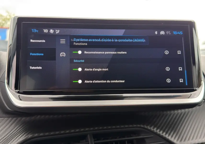 Écran tactile central affichant les réglages d’aides à la conduite dans l’habitacle d’une Peugeot 208 gris clair.
