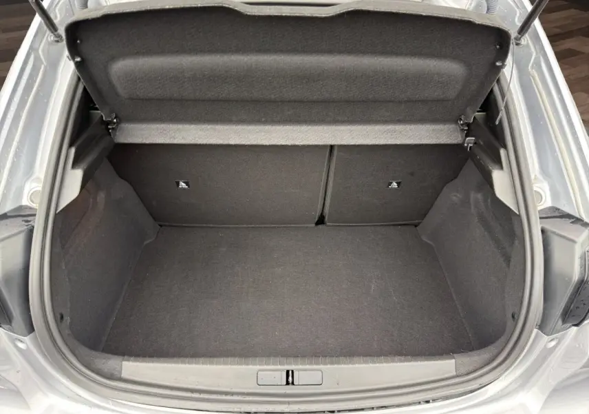 Vue plongeante sur le coffre ouvert gris clair de la Peugeot 208 2025, montrant un espace de rangement propre et spacieux.