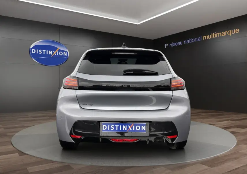 Vue arrière d'une Peugeot 208 gris clair 2025 avec feux LED et logo distinctif sur fond noir.