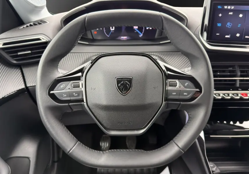 Vue rapprochée du volant cuir multifonctions de la Peugeot 208 2025 avec tableau de bord et écran tactile.