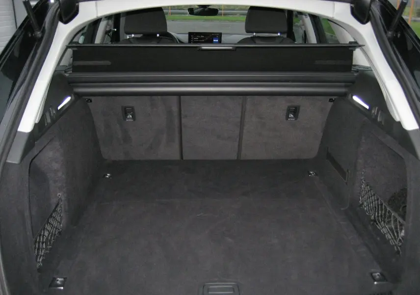 Coffre spacieux noir de l'Audi A4 Avant 3.5 TDI 2022 vu de l'arrière avec filet de rangement sur les côtés.
