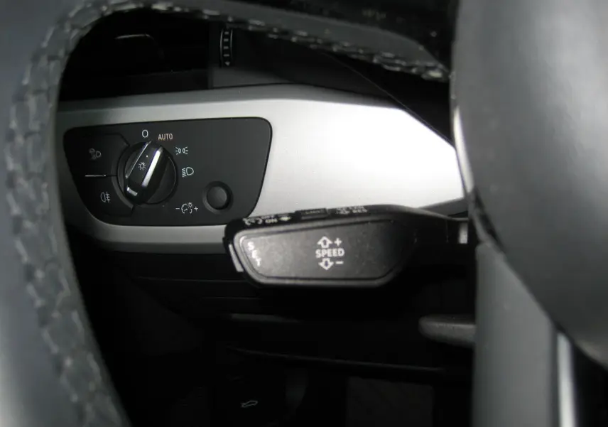 Gros plan sur le commodo de régulateur de vitesse et le sélecteur d'éclairage côté gauche du tableau de bord d'une Audi A4 Avant noire.