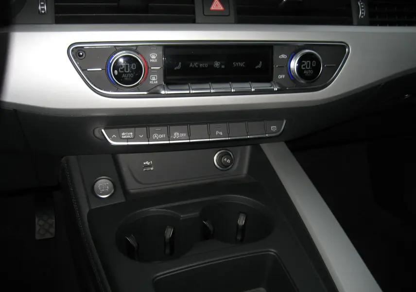 Vue rapprochée de la console centrale de l'Audi A4 Avant noire 2022, mettant en valeur la climatisation digitale et les commandes de conduite.