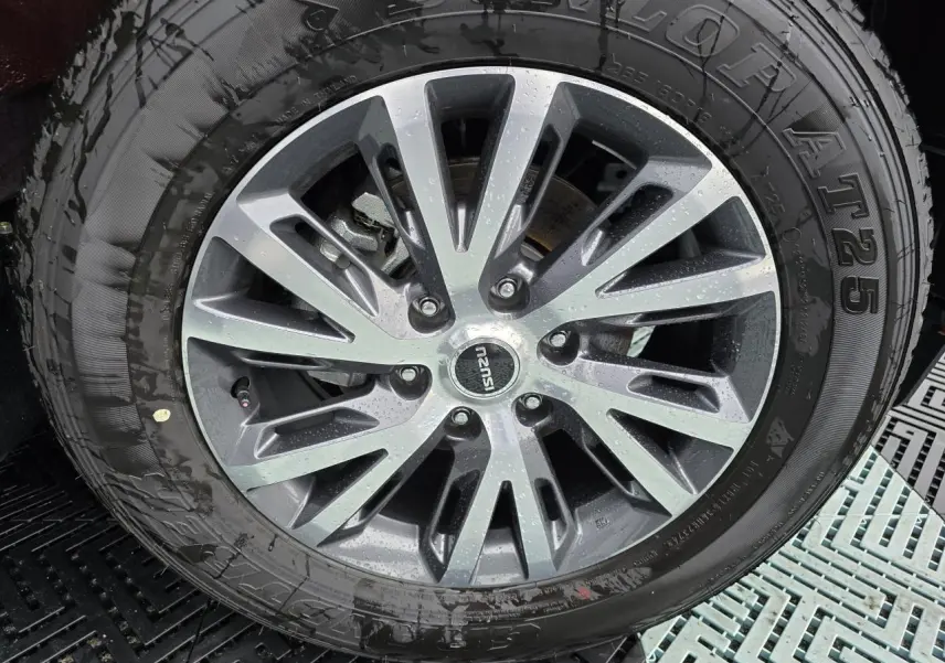 Vue rapprochée de la roue arrière gauche du pick-up Isuzu D-MAX orange métallisé avec jante alliage 18 pouces machining.