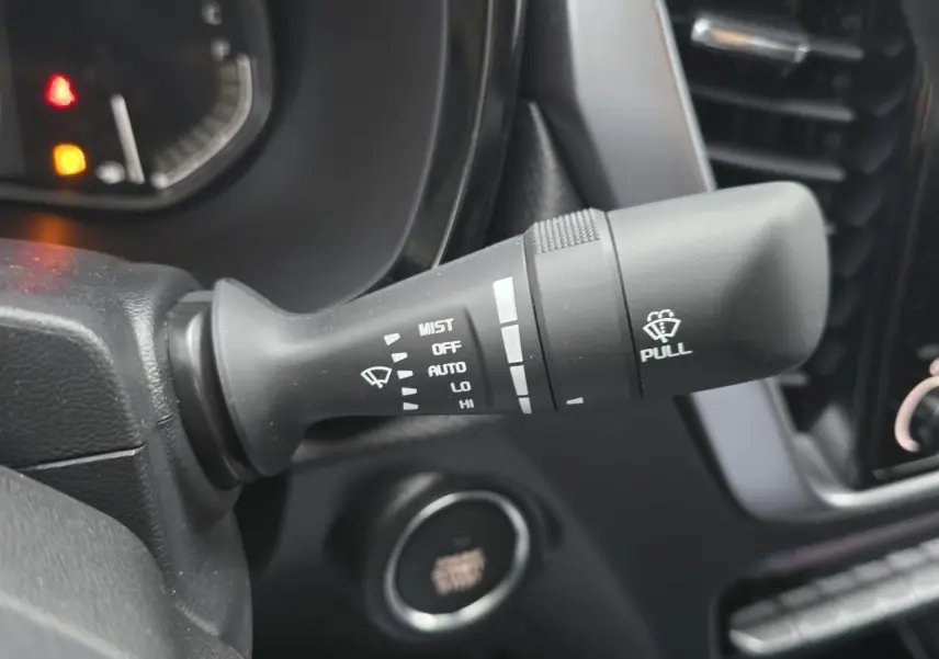 Gros plan sur la commande d’essuie-glace du tableau de bord noir d’un Isuzu D-MAX orange métallisé 2025.