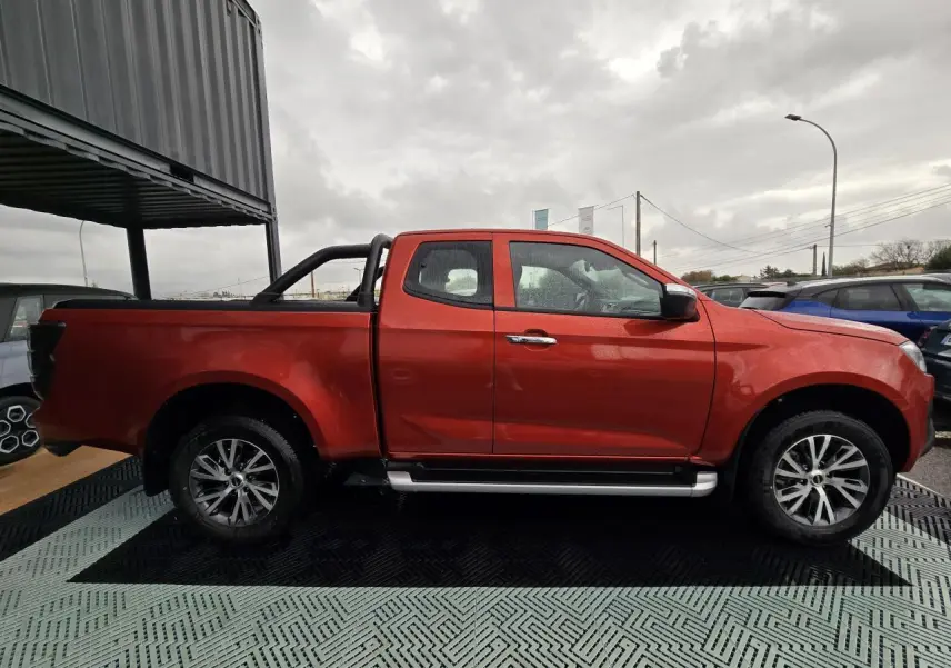 Vue de profil côté gauche d'un pick-up Isuzu D-MAX orange métallisé avec marchepieds argentés et arceau noir.