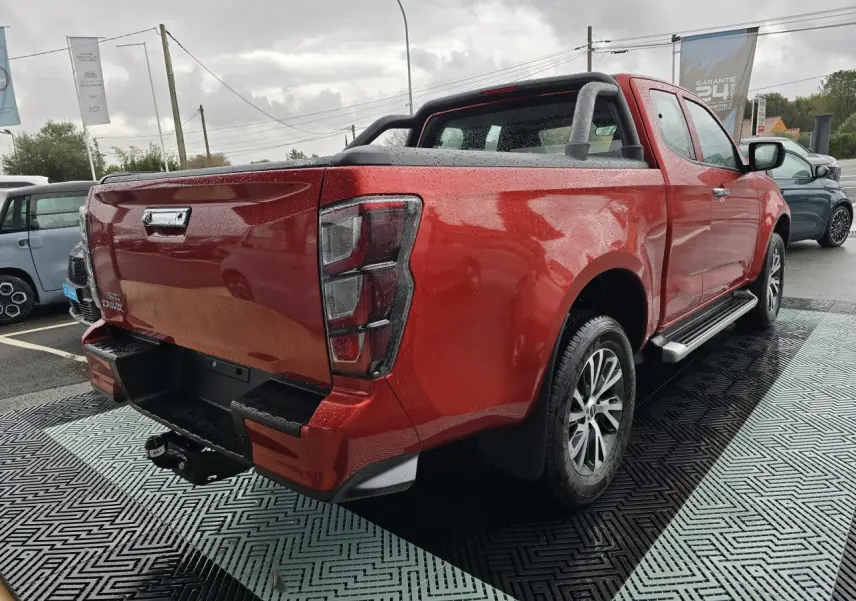 Vue 3/4 arrière droite d'un Isuzu D-MAX orange métallisé avec attelage et barres sport sur benne.