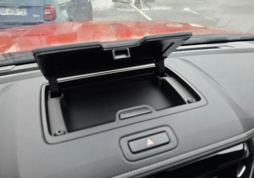 Détail de la console centrale ouverte du pick-up Isuzu D-MAX orange métal, avec bouton de signalisation au centre.