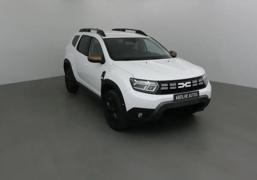 Dacia Duster blanc 4x4 vu en 3/4 avant droit avec rétroviseurs bronze et jantes noires.