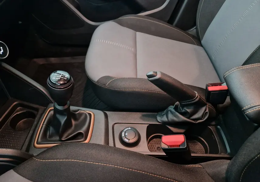 Vue rapprochée de la console centrale du Dacia Duster blanc 2024, montrant levier de vitesses manuel et frein à main.