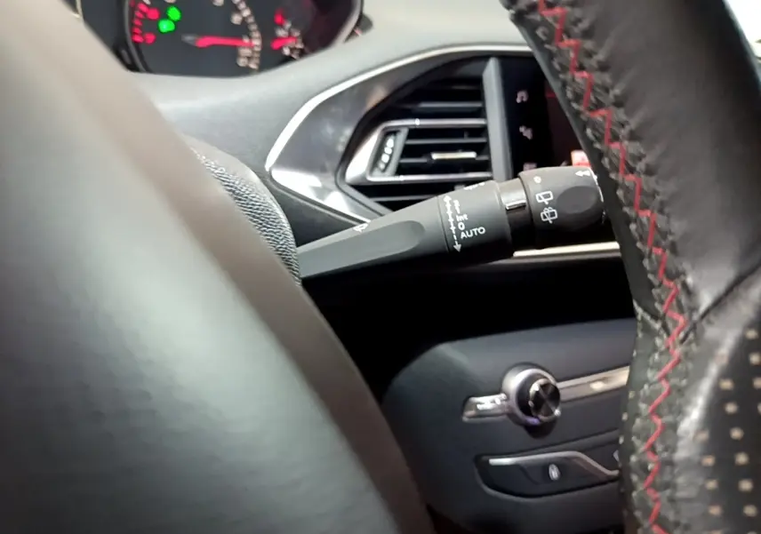 Détail intérieur du volant cuir noir avec surpiqûres rouges et commandes de la Peugeot 308 GT Line 2019.