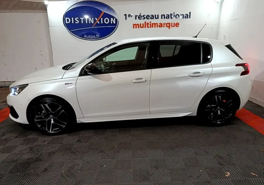 Profil côté gauche d'une Peugeot 308 Puretech 130 S&S GT Line blanche avec jantes noires dans un showroom.