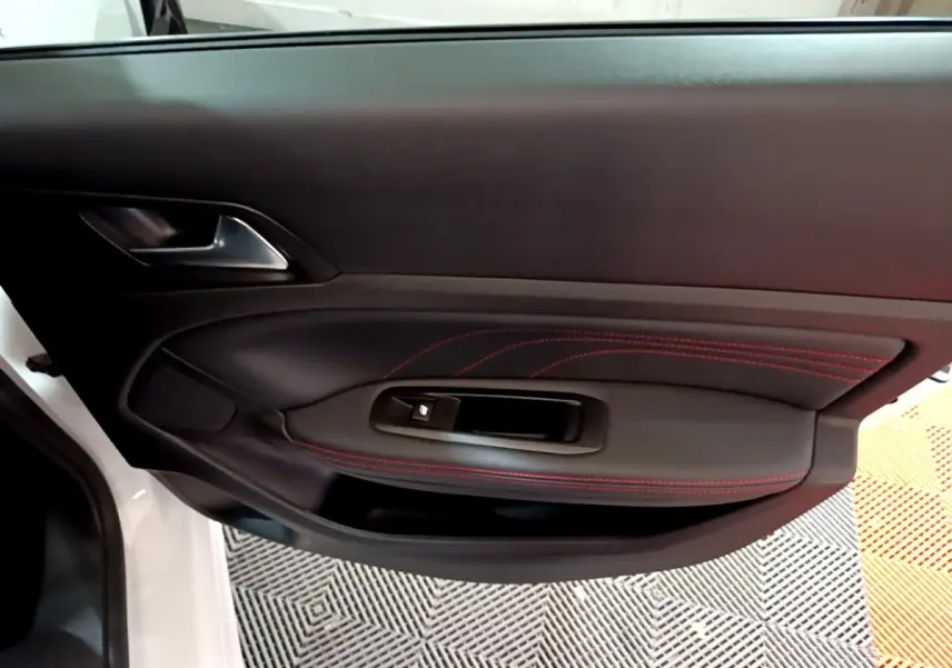 Gros plan sur la porte côté gauche blanche de la Peugeot 308 GT Line avec surpiqûres rouges et commande de vitre.