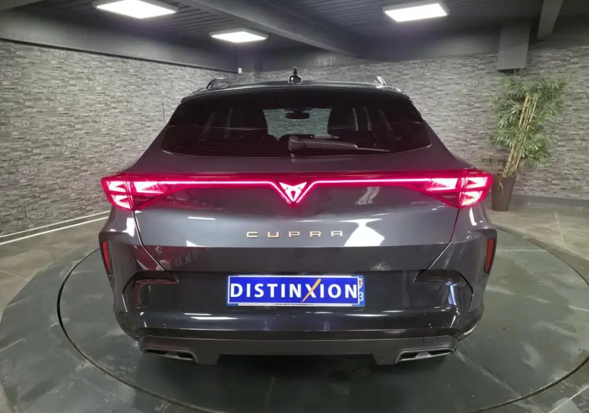Vue arrière d'une CUPRA Formentor gris métallisé avec signature lumineuse Tri-LED et double sortie d'échappement noire.