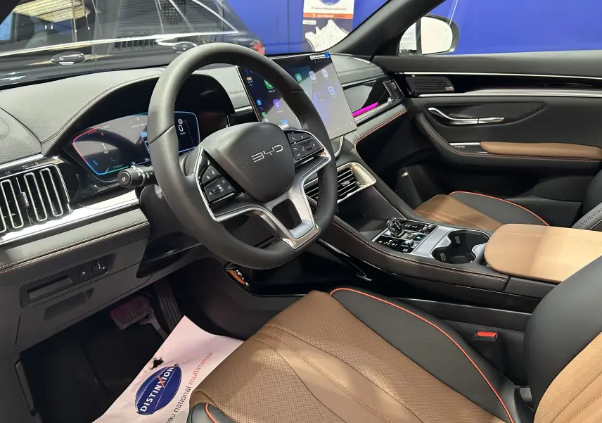 Vue intérieure côté conducteur du BYD SEAL U 2025 avec sièges cuir marron et tableau de bord numérique lumineux.
