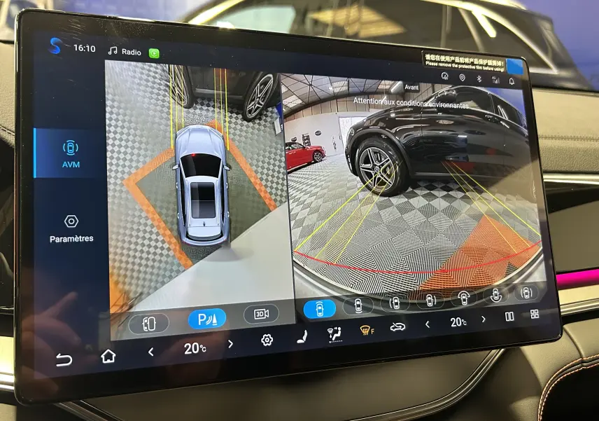 Écran intérieur affichant la caméra 360° et la vue arrière d’un véhicule noir dans un garage, avec lignes de guidage jaunes.