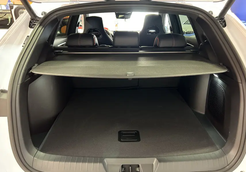 Vue arrière du coffre ouvert du BYD SEAL U blanc avec cache-bagages et sièges noirs visibles à l'intérieur.