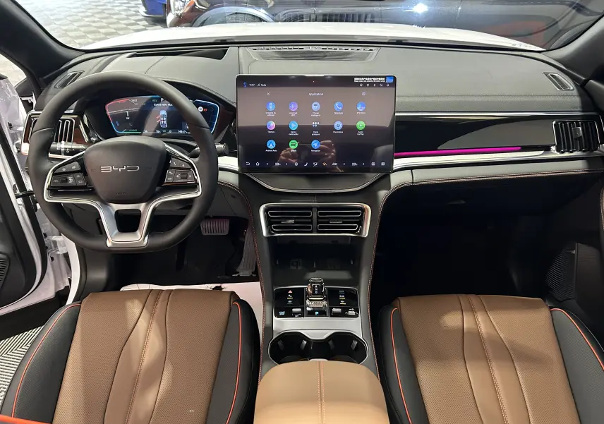 Vue intérieure avant du BYD SEAL U 2025 avec tableau de bord noir, écran tactile central et sièges cuir marron.