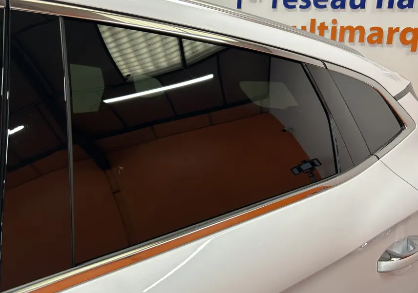 Gros plan sur la vitre arrière teintée côté droit d’un BYD SEAL U blanc nacré avec poignée de porte visible.