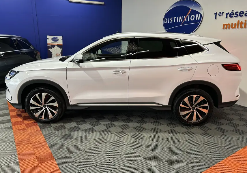 Vue de profil côté gauche d’un SUV BYD SEAL U blanc neige, avec jantes bicolores et vitres teintées, en intérieur showroom.