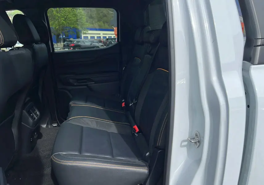 Vue intérieure côté droit sur la banquette arrière en cuir noir avec surpiqûres orange du Ford Ranger blanc glacier.