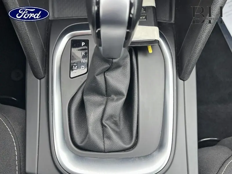 Le levier de vitesses automatique noir d'une Ford, vu de dessus, entouré de plastique gris et noir.