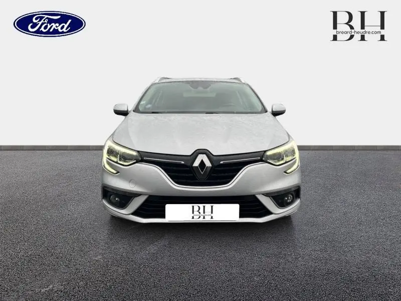 Vue avant d'une Renault Mégane Break gris platine avec feux LED allumés sur fond neutre.