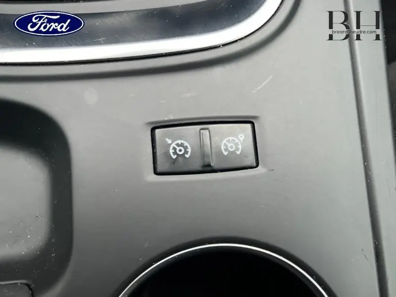 Bouton de commande du régulateur de vitesse sur la console centrale d’une Renault Mégane Break gris platine, vue rapprochée.