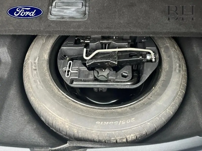 Vue rapprochée de la roue de secours et outils de bord dans le coffre d’une Renault Mégane Break gris platine.