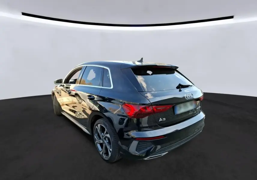 Audi A3 Sportback noire vue 3/4 arrière droit, avec jantes alliage 18'' et vitres arrière surteintées.