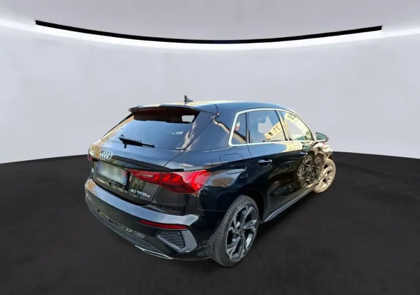 Audi A3 Sportback noir vue 3/4 arrière droit, avec jantes alliage 18'' et vitres arrière surteintées.