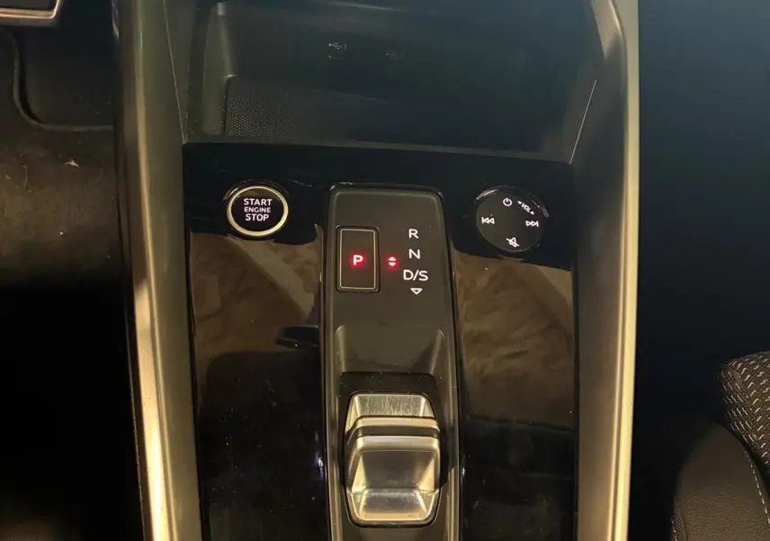 Vue plongeante sur la console centrale noire de l’Audi A3 Sportback 2023, avec levier de vitesse automatique et bouton start/stop.