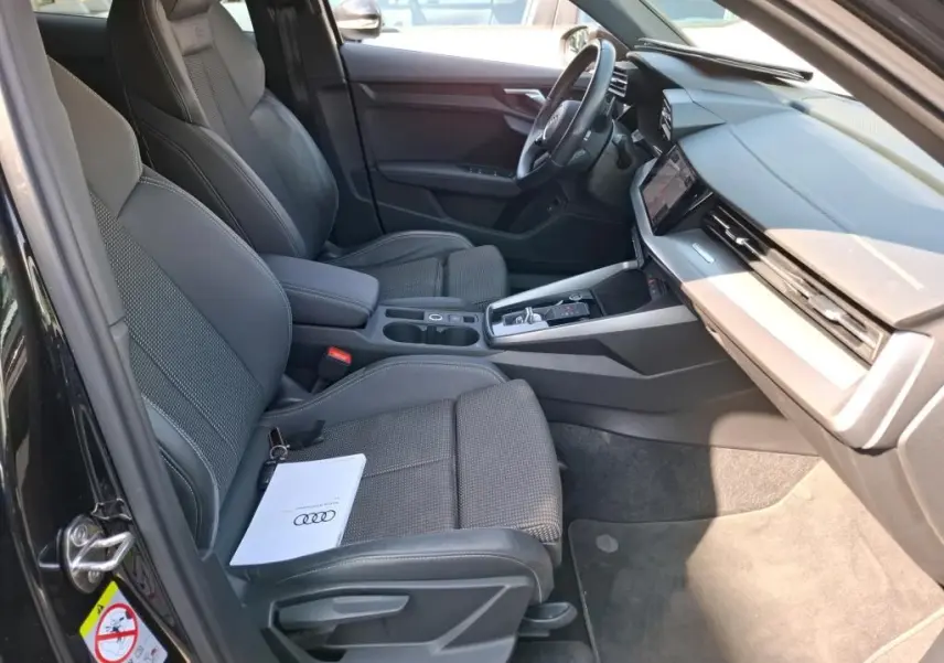 Vue intérieure côté conducteur de l'Audi A3 Sportback noire 2023, sièges sport en cuir et tableau de bord moderne.