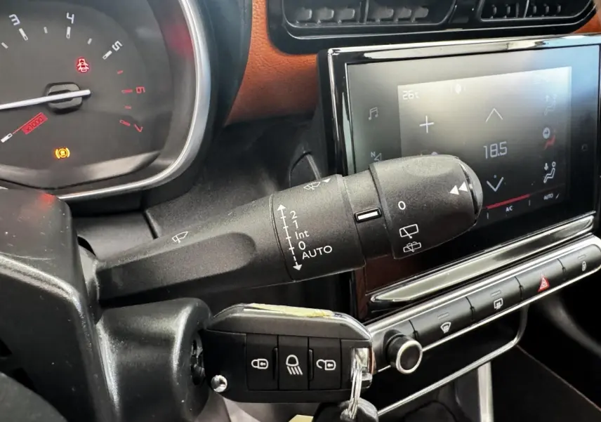 Gros plan sur la commande d’essuie-glace et la clé dans le contacteur d’un Citroën C3 Aircross noir, tableau de bord et écran tactile visibles.