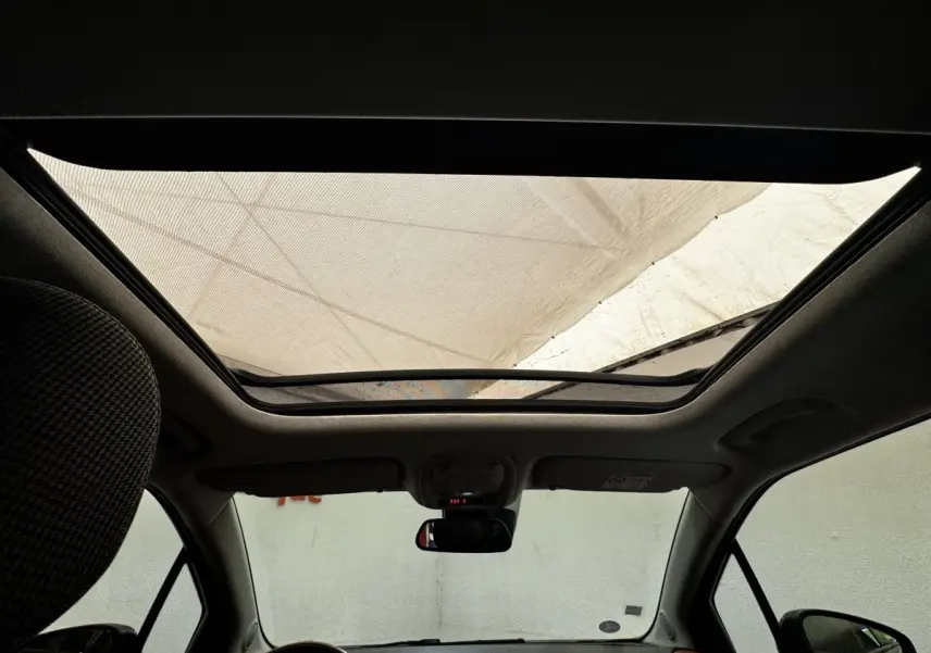 Toit panoramique ouvert vu de l'intérieur avant d'une Citroën C3 Aircross noire, avec rétroviseur central visible.