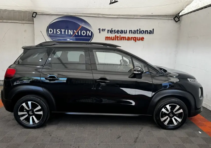 Vue latérale droite d'un Citroën C3 Aircross noir, avec jantes alliage bicolores et barres de toit noires visibles.