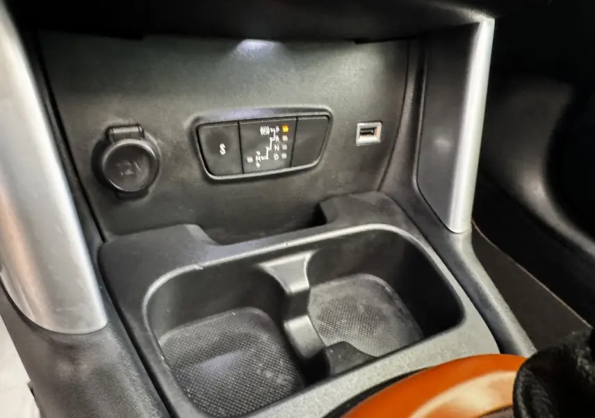 Gros plan sur la console centrale noire de la Citroën C3 Aircross 2020, avec prise 12V, port USB et rangement double.