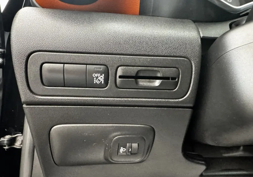 Gros plan sur les commandes latérales noires du tableau de bord d'une Citroën C3 Aircross noire, avec bouton d'assistance et réglage phare.