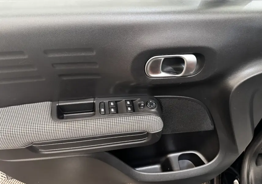 Gros plan sur la porte avant gauche noire du Citroën C3 Aircross 2020 avec commandes de vitres et poignée intérieure chromée.