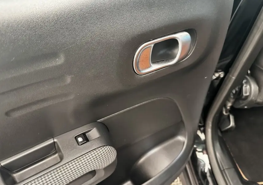 Gros plan sur la porte arrière gauche noire de la Citroën C3 Aircross 2020, avec poignée intérieure chromée et bouton de verrouillage.