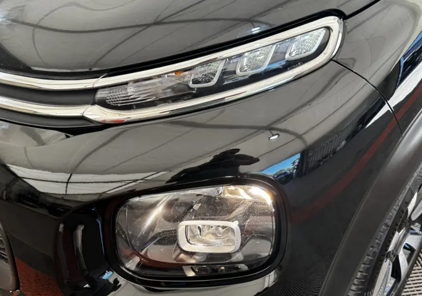 Gros plan sur le phare avant droit noir brillant du Citroën C3 Aircross 2020 avec détails LED et carrosserie lisse.