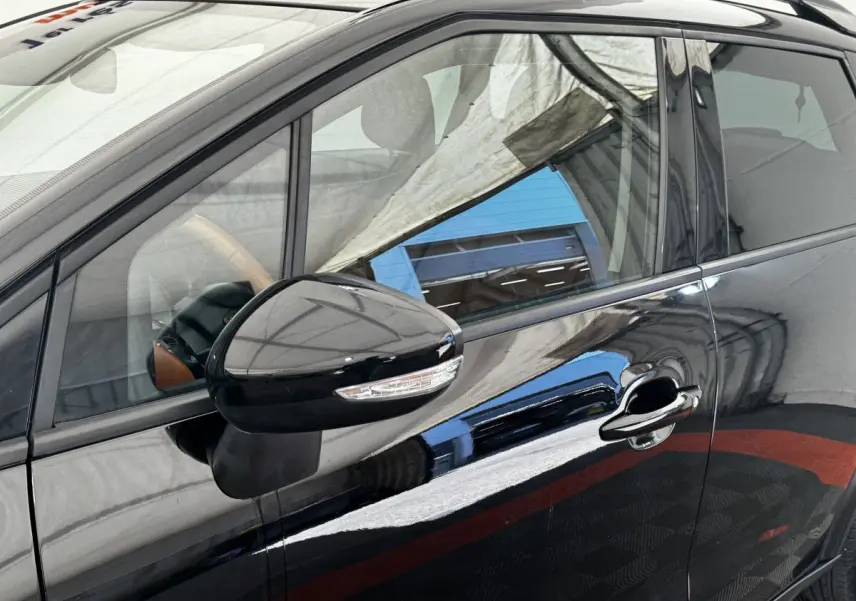 Vue rapprochée du côté gauche avant d'une Citroën C3 Aircross noire, mettant en valeur la poignée et le rétroviseur avec clignotant intégré.